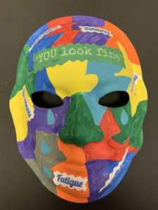 Unmasking Brain Injury mask painted with different colored sections with text "you look fine" "fatigue" and more