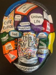 Unmasking Brain Injury mask painted with color segments with magazine text in the sections