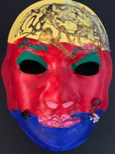 Unmasking Brain Injury mask painted yellow, red and blue with black swirls in the yellow section