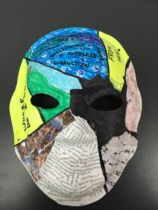 Unmasking Brain Injury mask painted with cracks with each section painted differently and with text on it