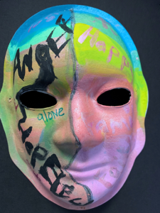 Unmasking Brain Injury mask painted with many bright colors and text of feelings