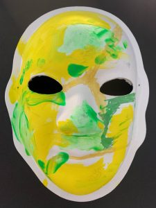 Unmasking Brain Injury mask painted with yellow and green